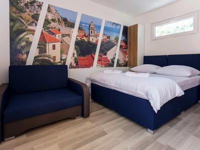 Modern hotel room with double bed, sofa, and large wall art depicting a cityscape.
