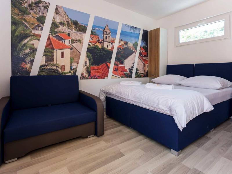 Modern hotel room with double bed, sofa, and large wall art depicting a cityscape.