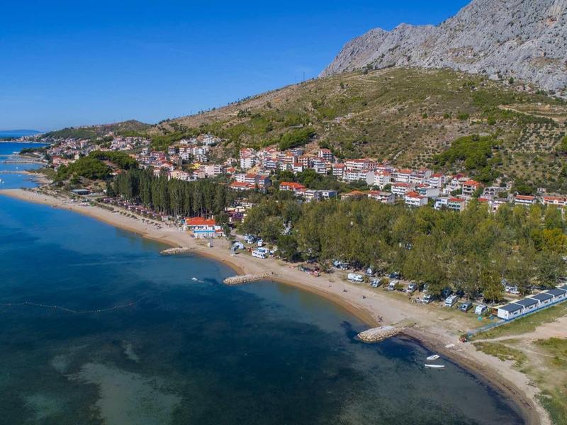 Coastal town with beach, mountains, and clear blue water under blue sky
