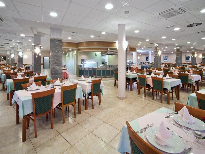 Großer Speisesaal mit vielen eingedeckten Tischen und Stühlen und heller Deckenbeleuchtung.