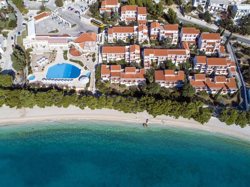 Luftaufnahme eines Hotelresorts mit Pool und direktem Zugang zu einem sandigen Strand am Meer.