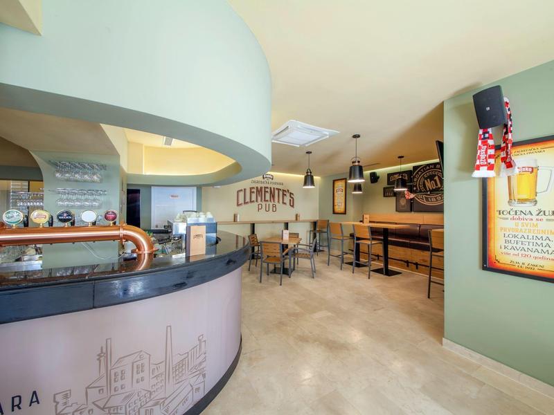 Moderne Hotel-Lounge mit Bartresen, Barhockern und Holztafeln an den Wänden.