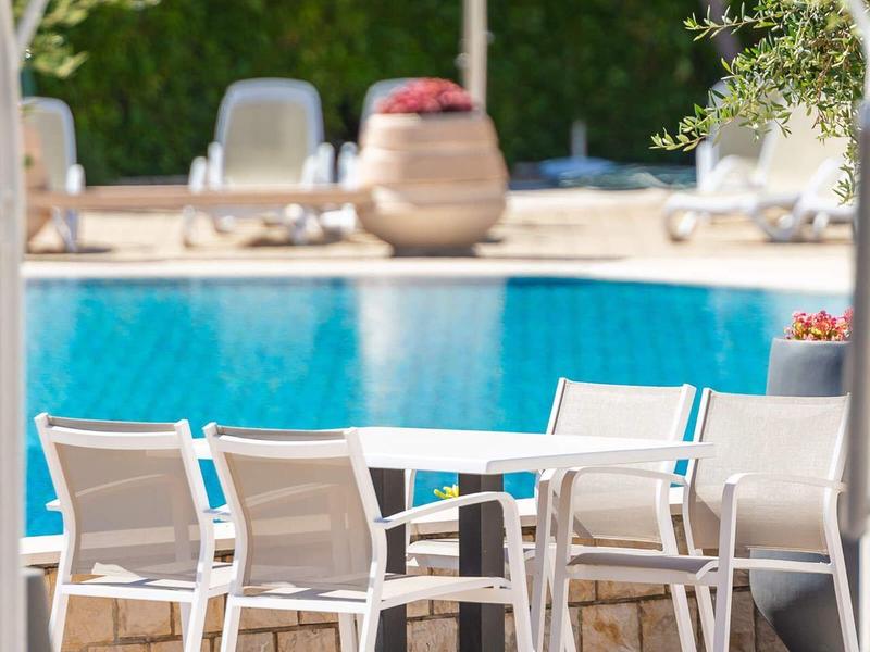 Moderner Außenbereich mit weißem Tisch und Stühlen neben einem Pool.