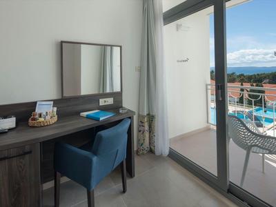 Moderner Schreibtisch mit Stuhl vor Balkon mit Blick auf Pool und Meer.