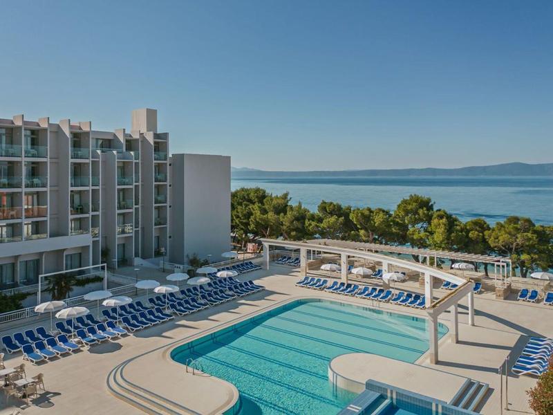 Piscine d'hôtel avec chaises longues et vue sur la mer sous un ciel clair