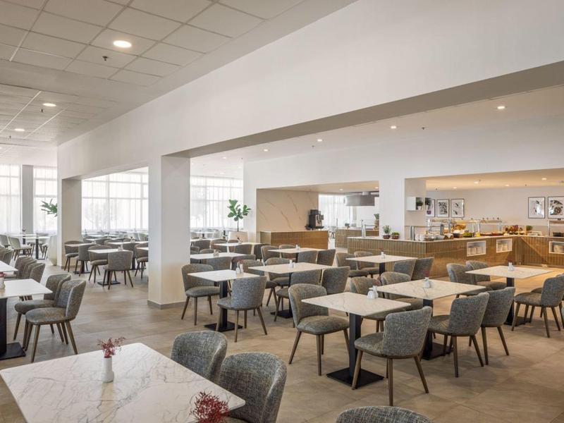 Restaurant lumineux et moderne avec de nombreuses tables et chaises aux couleurs neutres.