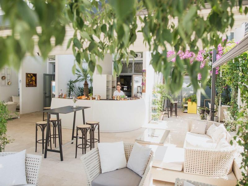 Salon lumineux avec sièges confortables et bar dans un hôtel moderne.