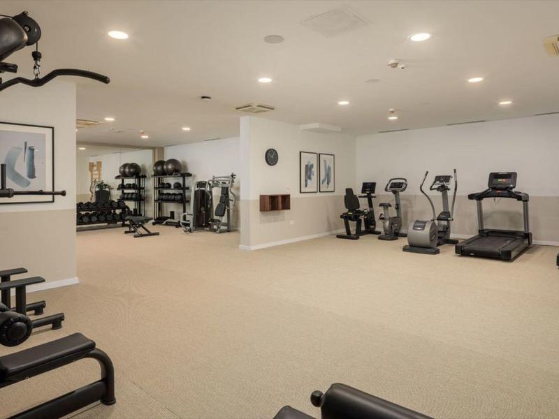 Grande salle de sport avec divers appareils d'entraînement et sol clair.