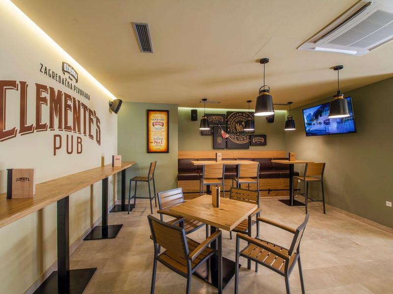 Pub accueillant avec tables en bois, chaises et décoration murale sous un éclairage chaleureux.