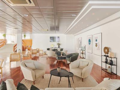 Moderner Hotel-Lounge-Bereich mit Sesseln, Sofas und Tischen auf Holzboden.