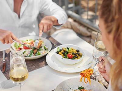 Zwei Personen genießen einen Salat zum Mittagessen in einem hellen Restaurant.