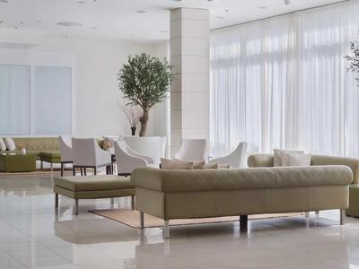 Moderner Hotel-Loungebereich mit großen Sofas, weißen Pflanzenvasen und viel Tageslicht.
