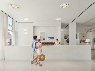 Moderne Hotellobby mit Empfangstresen, hellem Interieur und einem Paar beim Einchecken.