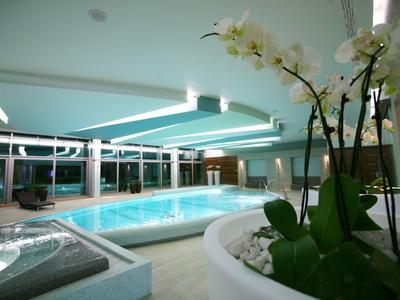 Hallenbad mit modernen Deckenleuchten und Blumendekoration im Vordergrund.