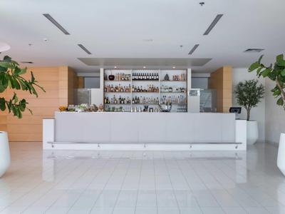 Modern hotel bar area with white counter and large potted plants