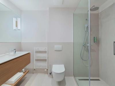 Bright bathroom with shower, toilet, wooden vanity, and towel warmer.