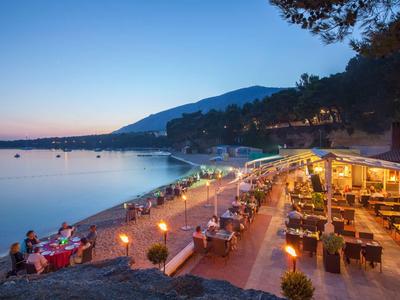 Beachside restaurant at sunset with lit tables and calm sea