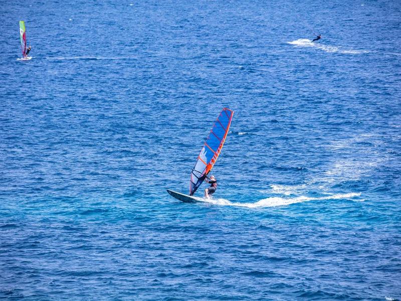 Windsurfer on open sea surrounded by deep blue water and wide view.