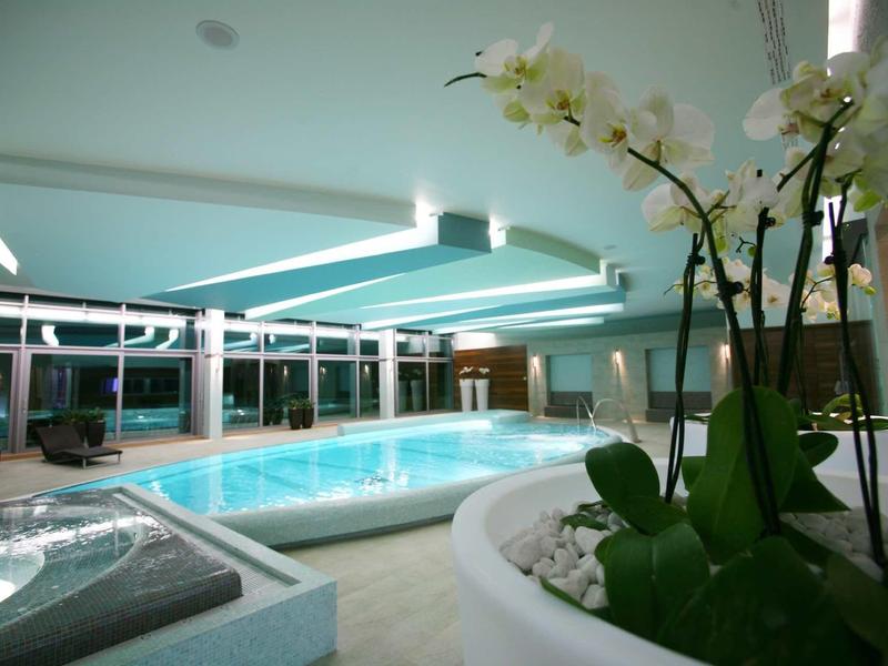 Large hotel complex by the beach with turquoise sea and wooded surroundings.