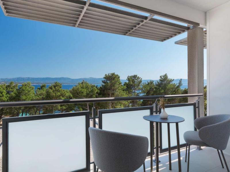 Balcony with two chairs and small table overlooking trees and mountains.