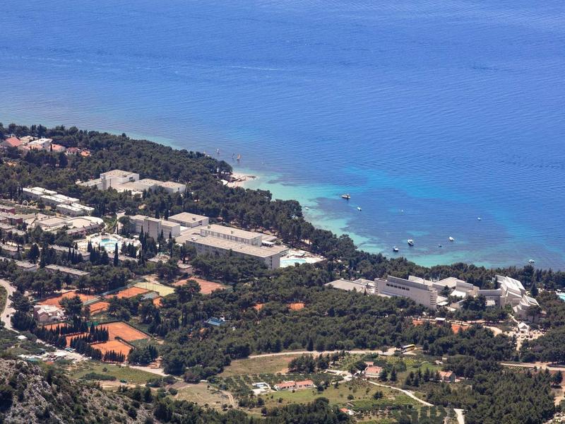 Coastal resort with several buildings and clear blue water in the background.