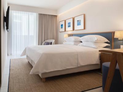 Modern hotel room with large bed, seating area, and wall art.