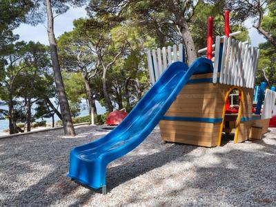 Blue children’s slide tower in an outdoor playground surrounded by trees.