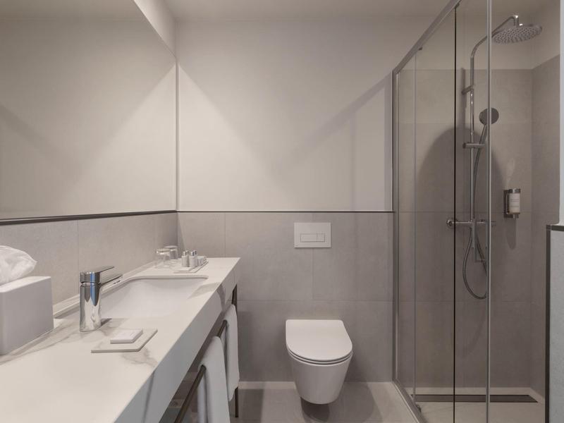 Modern bathroom with walk-in shower, toilet, and sink with large mirror.