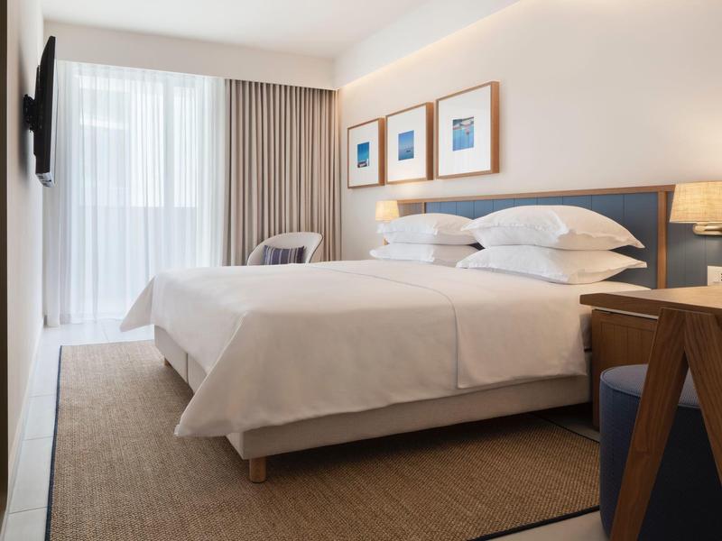 Modern hotel room with large bed, seating area, and wall art.