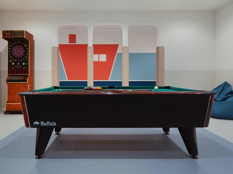 Billiard table in a modern room with beanbag and artistic wall mural.