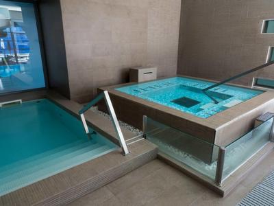 Moderner Spa-Bereich mit rechteckigem Pool und beheiztem Whirlpool in hellem Fliesenboden.