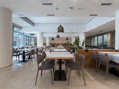 Modernes, helles Restaurant mit Holztischen und grauen Stühlen in einem Hotel.