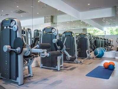 Moderne Fitnessgeräte und Gymnastikmatten in einem hellen Fitnessraum mit Spiegeln.
