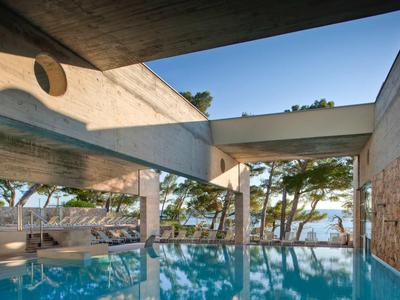 Moderner Innenpool mit klaren blauen Wasser, großem Fenster und Blick auf Bäume und Meer.