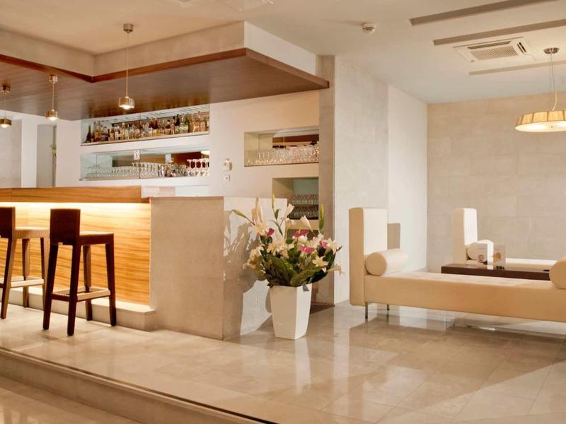 Helle, moderne Küche mit Holzmöbeln, Bank mit Kissen und eleganten Blumen in hellem Raum.