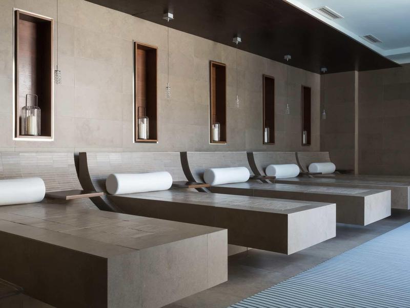 Moderner Wellnessbereich mit großen Liegen und integrierten Duftkerzen in Nischen an der Wand.