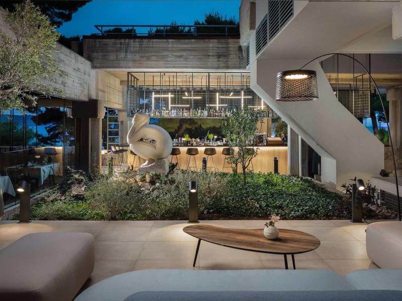 Moderner Außenbereich mit gemütlicher Lounge, Pflanzen, Bar und Treppe bei Dämmerung.