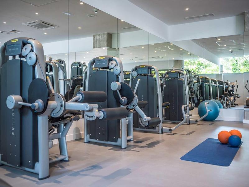 Fitnessstudio mit modernen Kraftgeräten, Trainingsmatte und Medizinbällen in hellem, großem Raum.