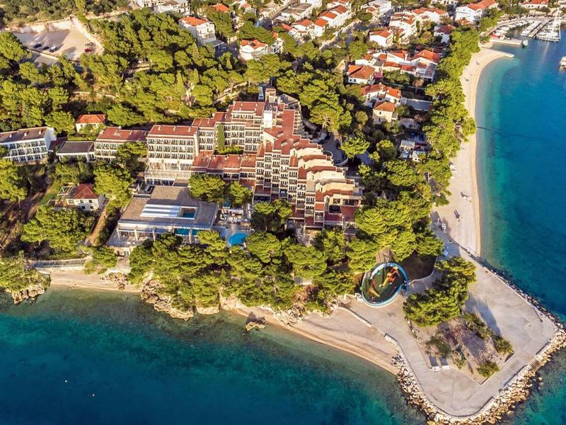 Luftaufnahme einer Küstenstadt mit Stränden, klar blauem Wasser und grünen Bäumen.