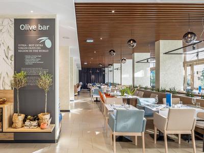 Modernes Hotelrestaurant mit Holzdecke, bequemen Stühlen und stilvoller Olive Bar.