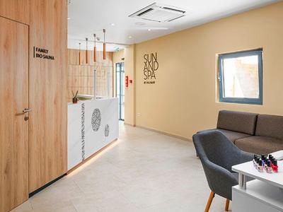 Heller Warteraum mit braunen Stühlen, Holzwand, Glasempfang und moderner Deckenbeleuchtung.