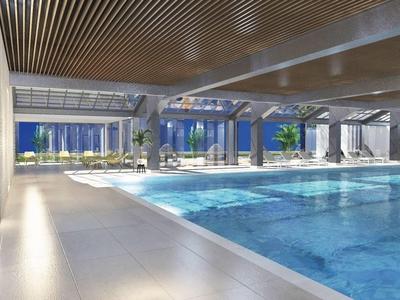 Großer Hallenbadbereich mit blauem Wasser, Glasfenstern und Holzdecke, helle Atmosphäre.