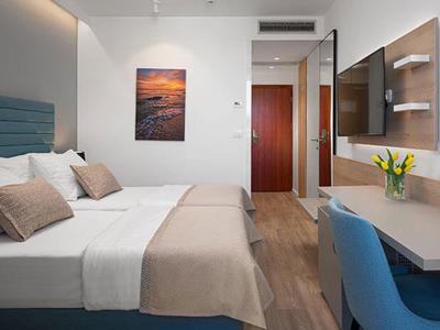 Modernes Schlafzimmer mit Doppelbett, blauen Akzenten, Holzfußboden und schlichtem Dekor.