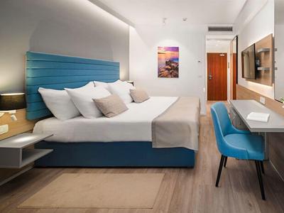 Modernes Hotelzimmer mit großem Bett, blauen Akzenten und Schreibtisch mit Stuhl.