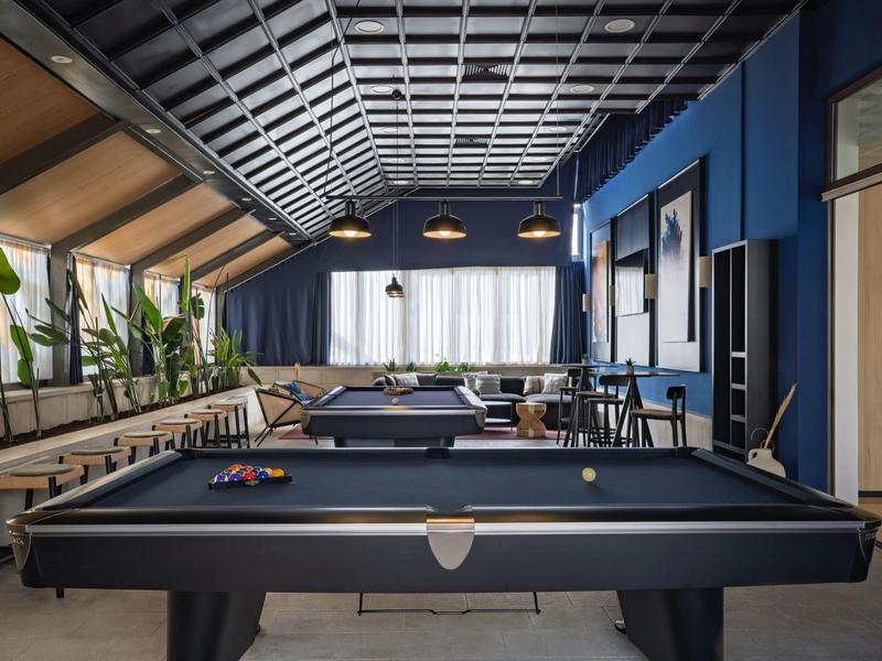 Moderner Raum mit Billardtischen und großen Fenstern in entspannter Atmosphäre.