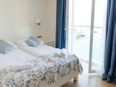 Hell eingerichtetes Hotelzimmer mit zwei Einzelbetten und Balkon mit Meerblick