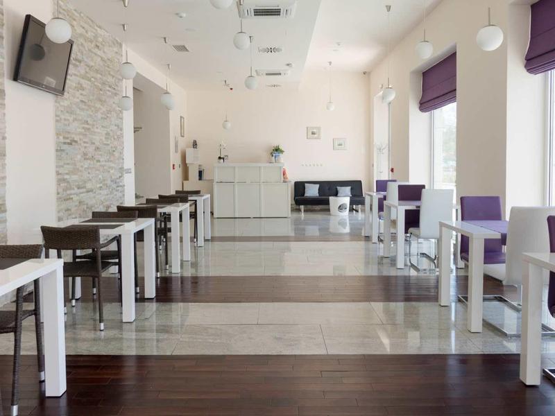 Moderne ontbijtruimte met wit en paars meubilair in een hotel.
