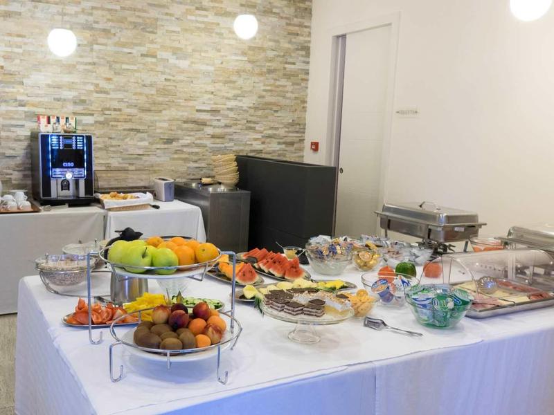 Buffet met verschillende gerechten en fruit in een lichte ruimte met een stenen muur.