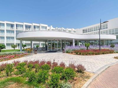 Moderner Hotel-Eingang mit Runddach und gepflegten Blumenbeeten.