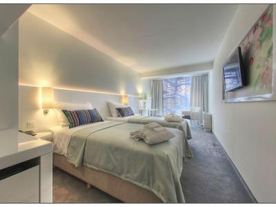 Modern eingerichtetes Hotelzimmer mit zwei Betten, TV und Fenster mit Blick nach draußen.